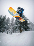 Snowboarder springt mit dem Ride Vantum Snowboard 2026/27 im verschneiten Wald