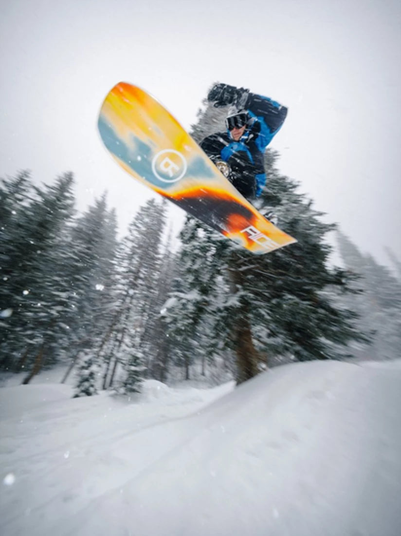 Snowboarder springt mit dem Ride Vantum Snowboard 2026/27 im verschneiten Wald