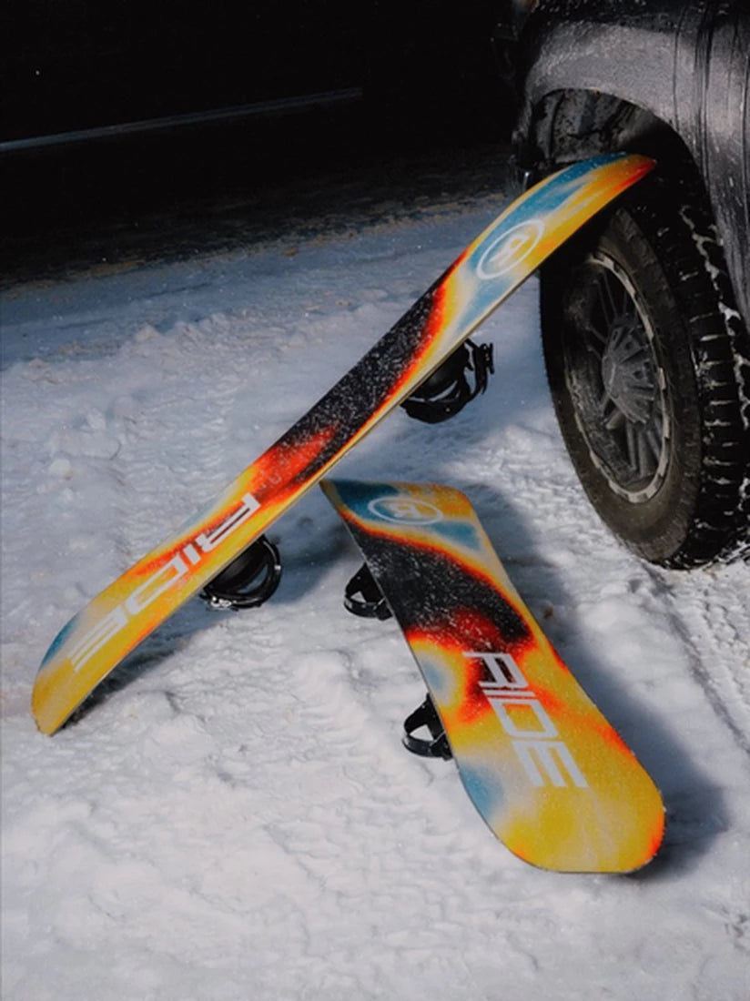 Zwei Ride Vantum Snowboards 2026/27 mit Bindungen im Schnee neben einem Autoreifen